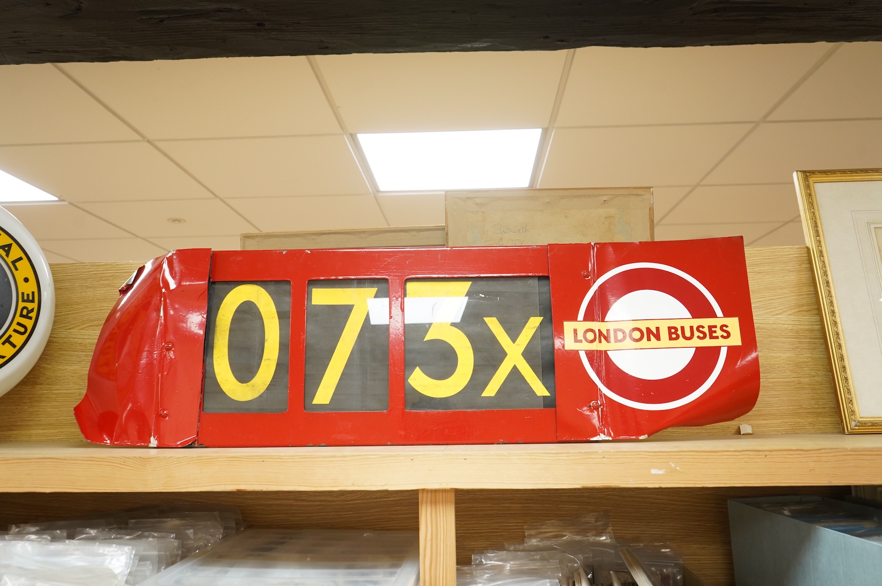 A London Transport bus destination blind box, complete with mechanism and three numerical destination blinds, with later applied sheets of red painted steel bolted to each side, mechanism with winding handle and row sele